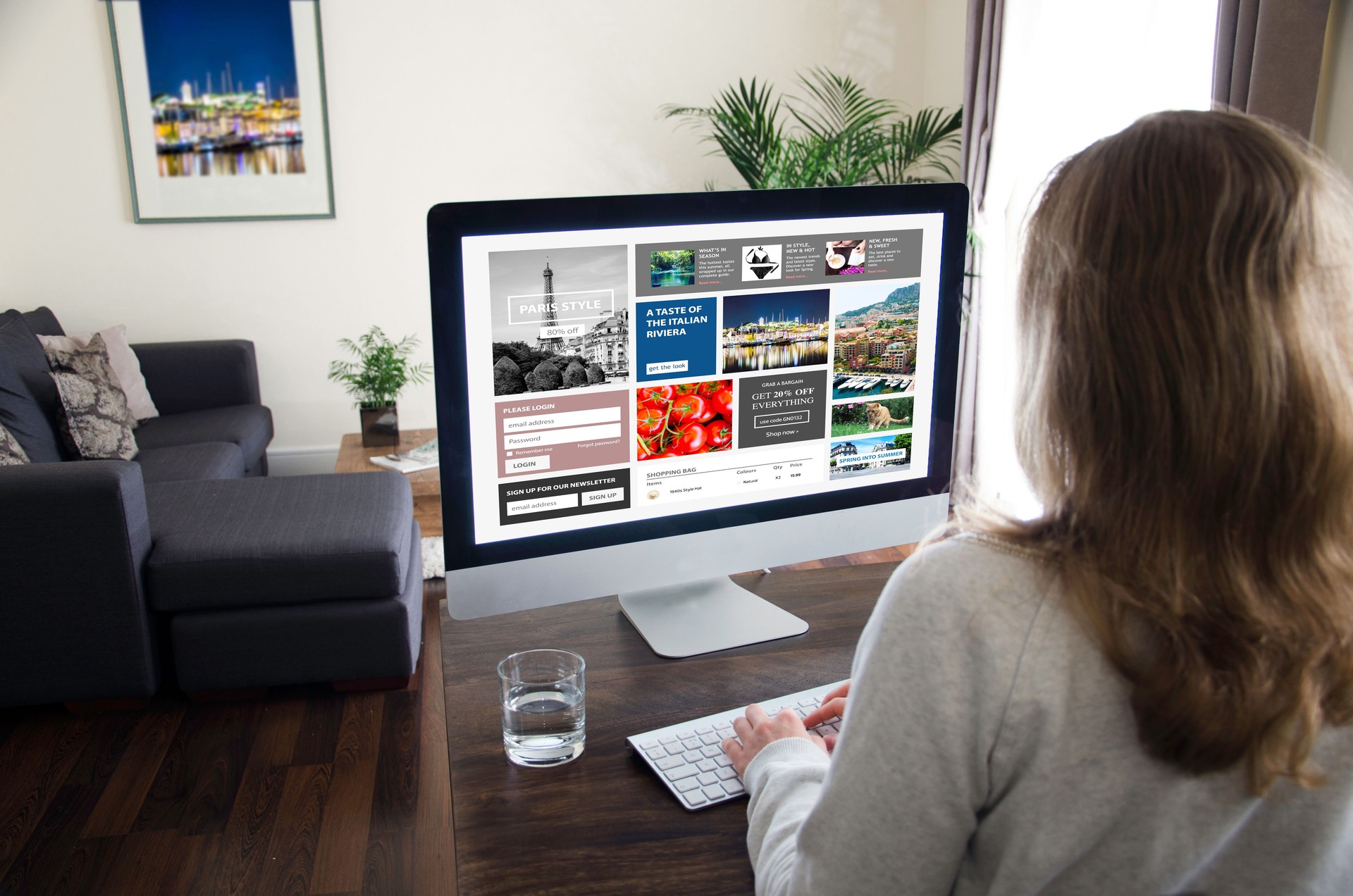 Blond woman sitting at home in a living room in front of a desktop computer